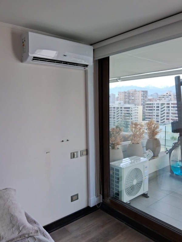 Dormitorio de departamento en Vitacura con equipo Split Muro instalado y unidad condensadora en la terraza.